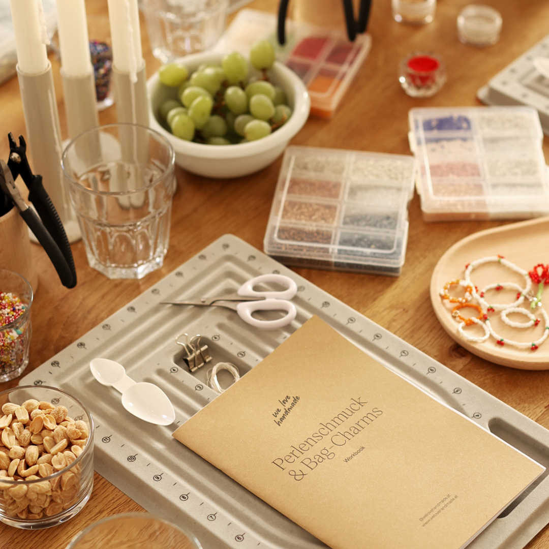 Bunte Perlenmischung, ein Glas Aperitivo und handgemachter Perlenschmuck auf einem sommerlich gedeckten Tisch im Studio in Wien. | we love handmade