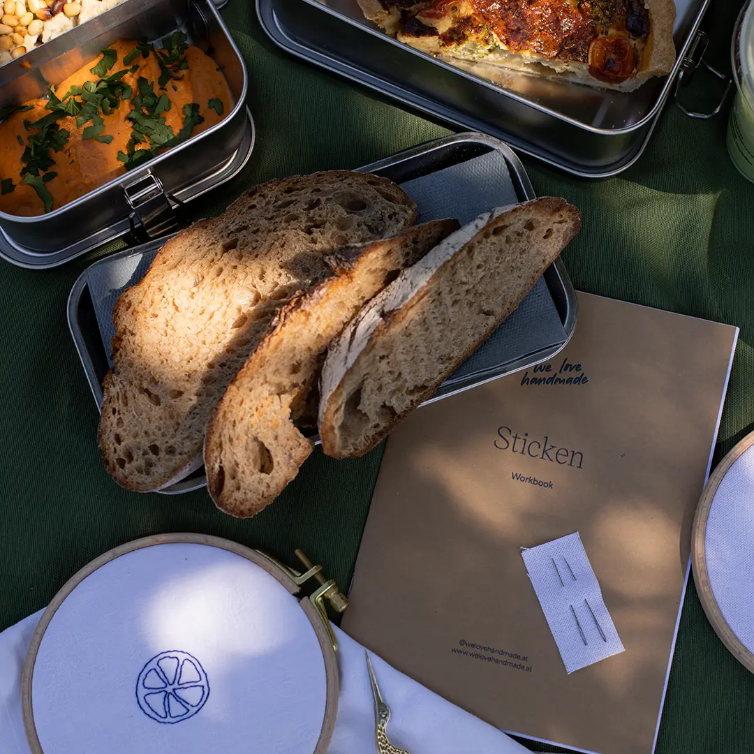 Frisches Sauerteigbrot und Dip aus dem SiL Picknickkorb neben dem Sticken Workbook von we love handmade