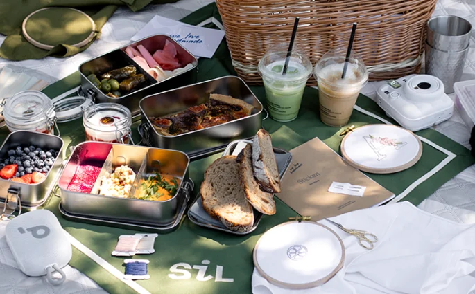 Picknickdecke im Burggarten mit SiL Tischtuch, Speisen in Edelstahldosen, Musikbox, Stickgarnen, Stickrahmen und Stick-Workbook